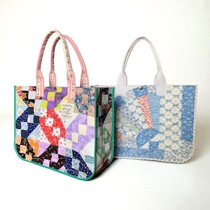 Könnte beinhalten: Zwei Patchwork-Tragetaschen. Eine Tasche hat ein farbenfrohes Patchwork-Design mit einem grünen Rand und rosa Blumenhenkeln. Die andere Tasche hat ein blau-weißes Blumenmuster mit weißen Henkeln. Beide Taschen sind rechteckig.