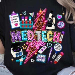May include: A black t-shirt featuring a colorful graphic with the text MED TECH life. The design includes a leopard print lightning bolt, a microscope, test tubes, a centrifuge, a clipboard with the words PRECISION PASSION PURPOSE, and a badge.