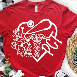 May include: Red t-shirt with a white graphic featuring a stethoscope, Caduceus symbol, floral elements, and the letters "PCT" inside a heart shape. The shirt is made of a soft material.