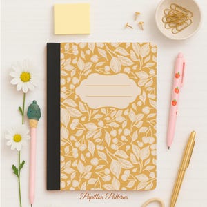 Peut inclure: Un cahier avec une couverture jaune ornée d'un motif de cerises et de feuilles blanches. Le cahier a un dos noir et une étiquette vierge. Un stylo rose avec des motifs de fraises, un stylo doré et d'autres articles de papeterie sont également présents.