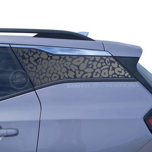 May include: A section of a light purple car window with a leopard print design. The design is a series of tan-colored spots. The text "SMITH CREATIONS" is visible on the window.