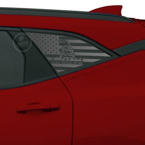 May include: Red car with a window decal featuring the American flag and the phrase "Don't Tread on Me." The decal is visible on the rear passenger window. The car has a black roof and a shark fin antenna.