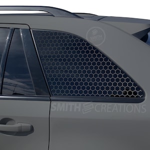 May include: A gray car with a black honeycomb window tint. The car has a black roof rack and a black rear spoiler. The text "SMITH CREATIONS" is visible on the car.