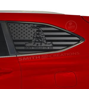 May include: A red car with a black and white American flag decal on the back window. The decal features a snake with the words "Don't Tread On Me".