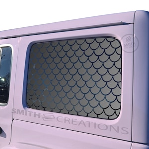 May include: A light purple vehicle with a window featuring a dark gray mermaid scale pattern. The text "SMITH CREATIONS" is visible on the vehicle's side. The window is rectangular with rounded corners.