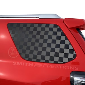 May include: Red vehicle with a checkered pattern window decal. The decal is black and gray. The text "SMITH CREATIONS" is visible on the vehicle.
