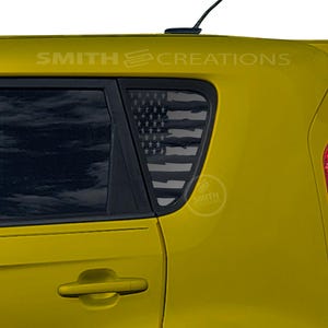 May include: A yellow car with a black and gray American flag design on the rear window. The text "SMITH CREATIONS" is visible above the window. A small logo is on the window.