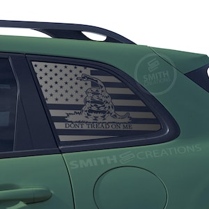 May include: A green SUV with a black and white American flag and a snake with the words "Don't Tread On Me" on the rear window.