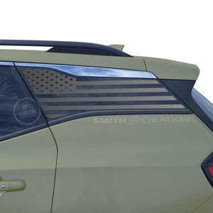 May include: A green SUV with a black American flag decal on the rear window. The decal is a silhouette of the American flag with black stars and stripes.