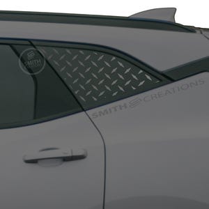 May include: A section of a light gray car with a diamond plate pattern on the rear window. The text "SMITH CREATIONS" is visible on the car's body. A small logo is also visible on the window.
