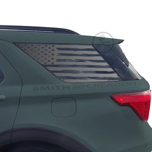 May include: A dark green SUV with a rear window graphic of the American flag. The flag design is distressed, with faded stripes and stars. The text "SMITH CREATIONS" is printed below the window.