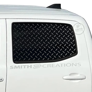 May include: White truck with a black diamond plate window insert. The text "SMITH CREATIONS" is printed on the side of the truck. A logo is also visible on the side of the truck.