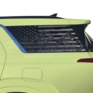May include: A light green SUV with a rear window decal featuring an American flag design with floral accents. The decal is white and the text "SMITH CREATIONS" is visible on the vehicle.