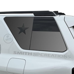 May include: White SUV with a Texas flag design on the rear window. The flag features a dark gray star and stripes. The text "SMITH CREATIONS" is printed on the vehicle.