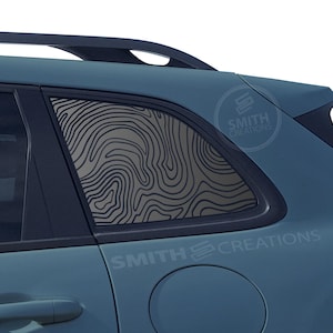 May include: A blue car with a black window decal of a topographic map design. The decal is on the back passenger window. The car has a "SMITH CREATIONS" logo on the side.