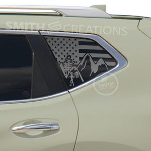 May include: A cream-colored vehicle with a window decal featuring an American flag design, mountains, and a figure. The decal is gray and the text "SMITH CREATIONS" is visible on the vehicle.