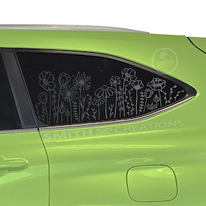 May include: A lime green car with a rear window featuring a white floral design. The design includes flowers, leaves, and stems. The text "SMITH CREATIONS" is visible on the car.