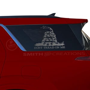 May include: A red SUV with a window decal of a coiled snake with the text "Don't Tread On Me". The decal is in white and is on the back passenger side window. The text "Smith & Creations" is also on the decal.