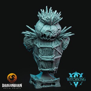 Può includere: Un busto in resina grigia di una creatura con un corpo a forma di cesta intrecciata, una testa spinosa e un'espressione minacciosa. Il busto è su una base grigia con un logo Witchsong.