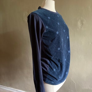 May include: A navy blue long-sleeved shirt with a geometric pattern on the front. The shirt is made of a soft, textured fabric.
