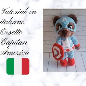 Può includere: Un orsetto di peluche all'uncinetto vestito da Capitan America, con maschera e tuta blu, stella bianca, stivali rossi e uno scudo. L'orso è marrone e blu, con il testo "Tutorial in italiano Orsetto Capitan America" e una bandiera italiana.