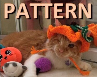 Puede incluir: Un gato jengibre con un sombrero de calabaza de ganchillo, con un pecho y patas blancas, está acostado con un juguete de peluche de calabaza y un juguete de peluche morado. El gato está mirando a la cámara con un ojo cerrado.