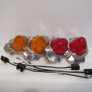 Puede incluir: Conjunto de cuatro luces automotrices cromadas con lentes naranjas y rojas. Las luces tienen forma de cono y están conectadas por cables.
