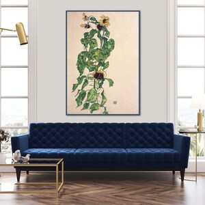 May include: A painting of a sunflower plant with yellow flowers and green leaves on a light beige background. The painting is framed in a black frame and is hanging on a white wall.