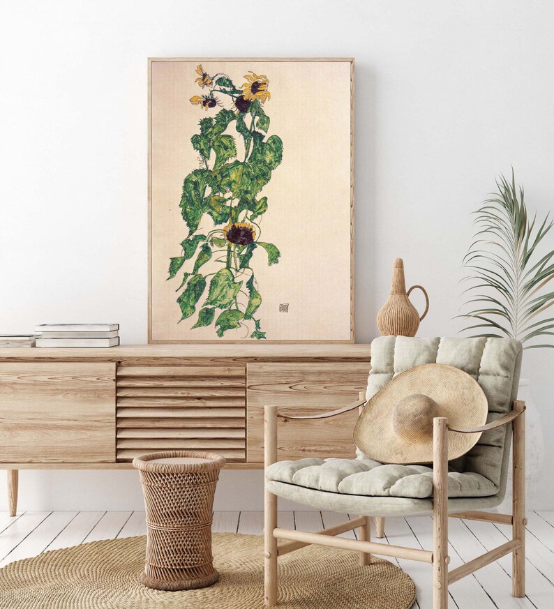 May include: A framed print of a watercolor painting of a sunflower plant with green leaves and yellow petals. The painting is on a cream background.