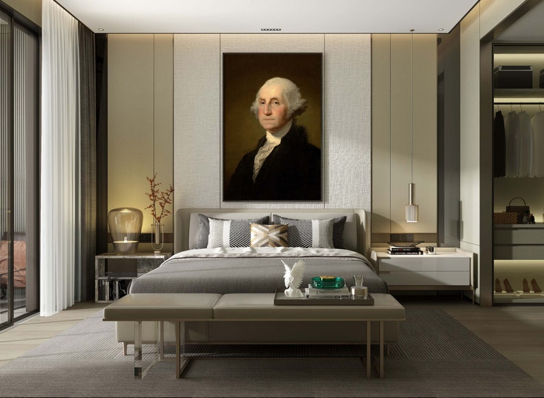 May include: A bedroom interior with a large framed portrait of George Washington hanging above a gray upholstered bed with white and brown patterned pillows. The bed is positioned in front of a wall with a textured beige wallpaper. There is a white nightstand on each side of the bed with a lamp on each nightstand. A white bench sits in front of the bed. The room has a large window with white curtains and a gray rug on the floor.