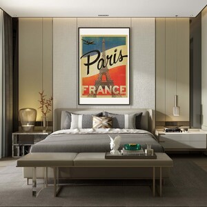 Op de afbeelding: Een slaapkamerinterieur met een grijs bed, een grijze bank en een ingelijste poster met de tekst "Paris France" en een afbeelding van de Eiffeltoren. De poster hangt aan een muur met een textuur.