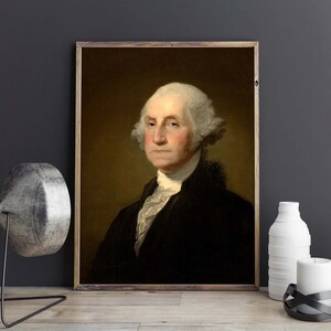 May include: A portrait painting of George Washington, the first president of the United States. He is wearing a black coat with a white cravat and has a powdered wig. The painting is framed in a wooden frame.