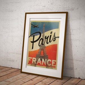Op de afbeelding: Een vintage poster met een bruin frame met daarop de Eiffeltoren in Parijs, Frankrijk. De poster heeft een blauw, wit en rood kleurenschema en de tekst "Paris France" is in zwart gedrukt.