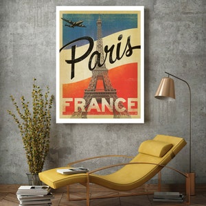 Op de afbeelding: Vintage reisposter met de Eiffeltoren in Parijs, Frankrijk. De poster heeft een rood-wit-blauw kleurenschema met een vliegtuig dat erboven vliegt. De tekst "Paris France" is in zwart gedrukt.