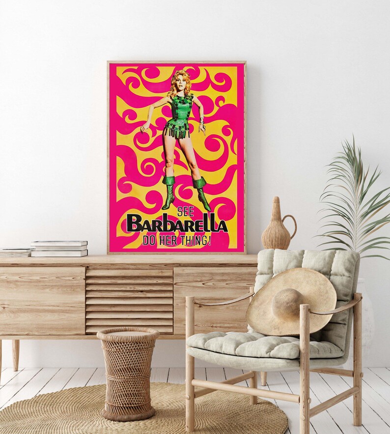 Puede incluir: Un p&oacute;ster de pel&iacute;cula vintage para la pel&iacute;cula "Barbarella" con una mujer con un traje verde y botas de pie sobre un fondo rosa y amarillo con patrones en espiral. El texto en el p&oacute;ster dice "See Barbarella Do Her Thing!"