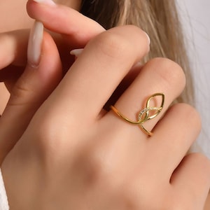 Woman wearing teardrop infinity diamond ring, geometric statement ring styled on hand with yellow gold finish