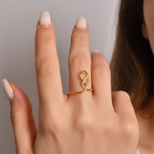 14K solid gold teardrop infinity ring with diagonal diamond line, geometric frame design, pavé set stones, white background
