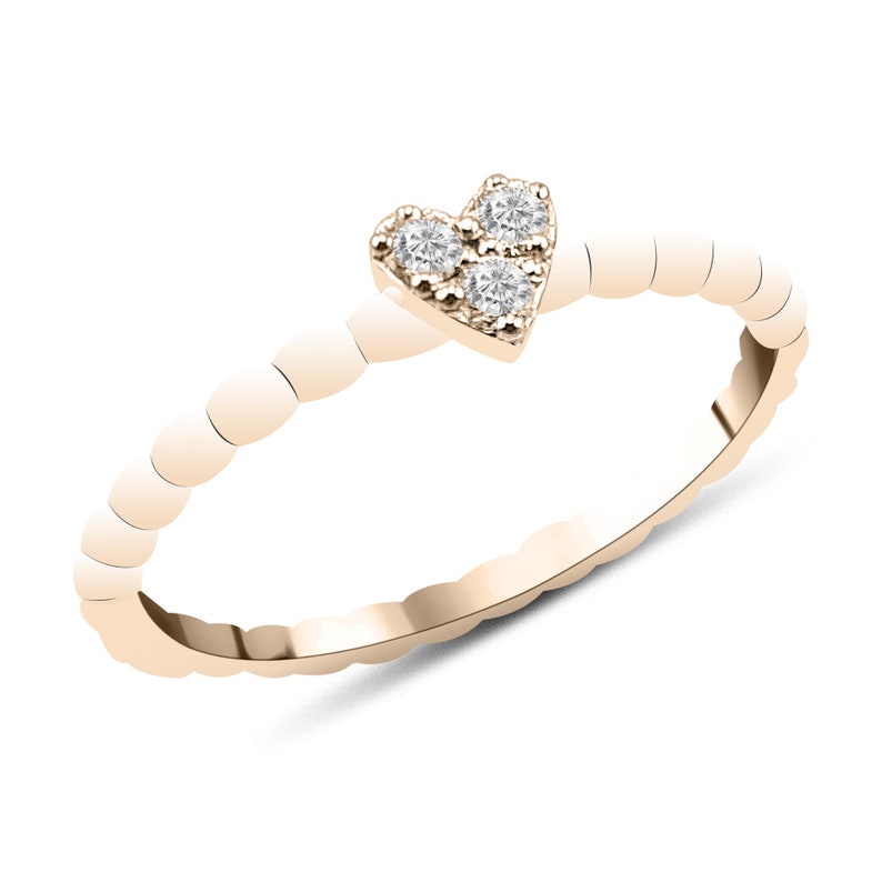 May include: A delicate gold ring with a heart-shaped design featuring three small diamonds.