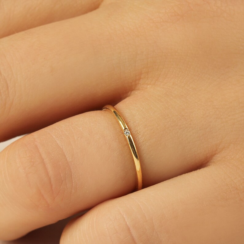 Close-up of prong-set 1.10mm round diamond on ultra-slim 1.20mm band, minimalist 8K gold solitaire ring