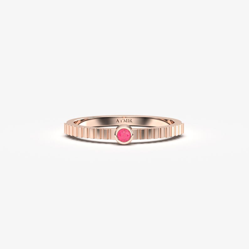 Pu&ograve; includere: Anello in oro rosa con una gemma rosa al centro. La fascia presenta un design a coste. L'anello &egrave; un gioiello delicato, perfetto per l'uso quotidiano. Il marchio "AYMIR" &egrave; inciso sull'anello.