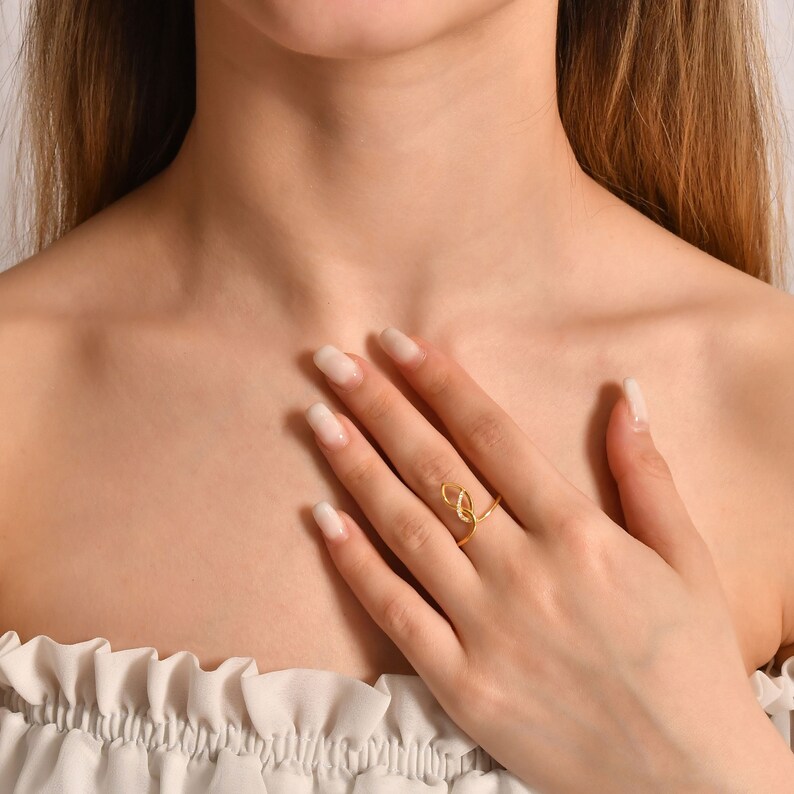 A gold ring with a delicate, intertwined design. The ring features a small, clear stone in the center.