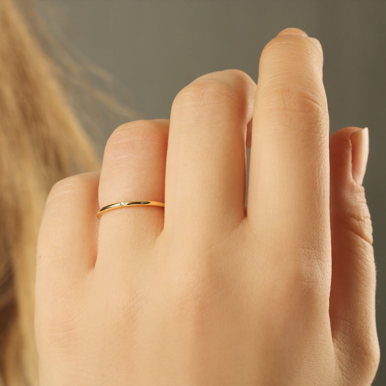 K&ouml;nnte beinhalten: Ein d&uuml;nner Goldring mit einem kleinen, klaren Stein in der Mitte.