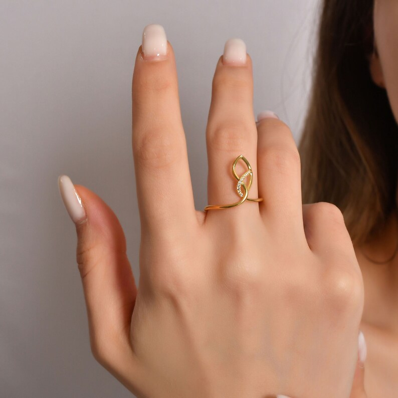 14K solid gold teardrop infinity ring with diagonal diamond line, geometric frame design, pavé set stones, white background
