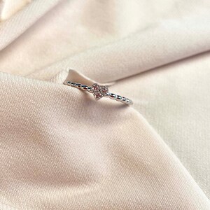 Close-up of three 1.70mm round natural diamonds arranged in heart shape cluster with prong setting on gold beaded band ring