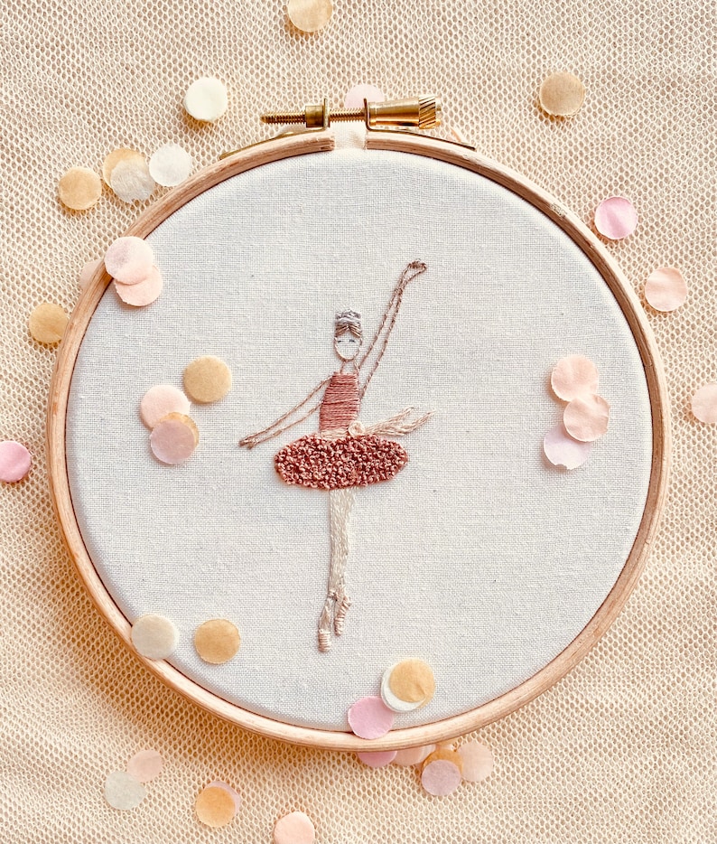 May include: A hand-stitched embroidery hoop featuring a ballerina in a pink dress. The hoop is surrounded by confetti.