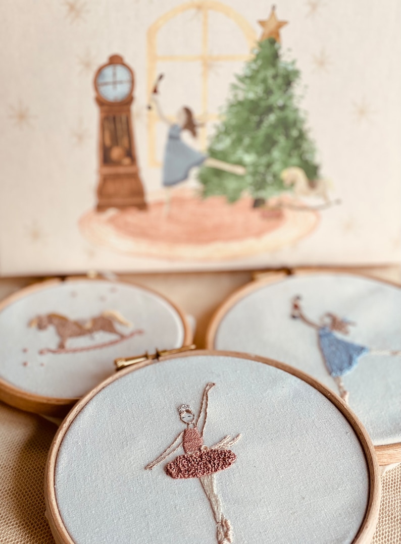 May include: Three embroidered hoop art pieces with a white background. One hoop features a rocking horse, another features a ballerina in a pink tutu, and the last hoop features a ballerina in a blue dress.