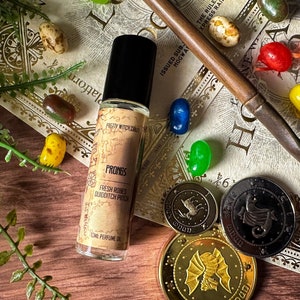 Puede incluir: Un frasco de perfume "Prongs" con el texto "Fresh Roses Quidditch Patch", rodeado de coloridas gominolas, una varita y monedas decorativas. El fondo incluye papel de estilo vintage con texto.