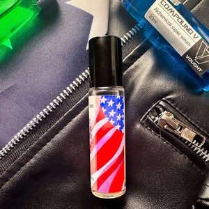 May include: A small glass bottle with a black cap and a label featuring an American flag design. The bottle is labeled "COMPOUND V Alchemical super serum 20ml VAUCHT".