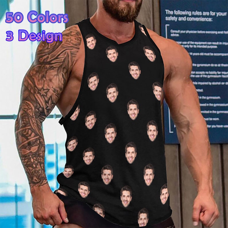 May include: A black sleeveless tank top with a repeating pattern of a man's face. The tank top is being worn by a person with tattoos on their arm.