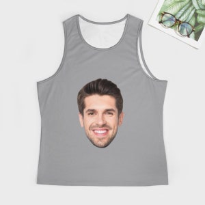 May include: A gray tank top with a white face printed on the front. The face is of a man with brown hair and a smile.